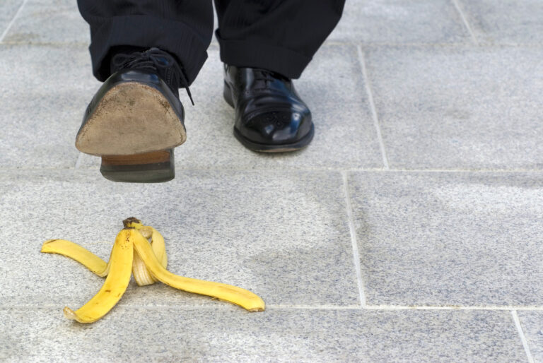 Businessman stepping on banana skin, copy space