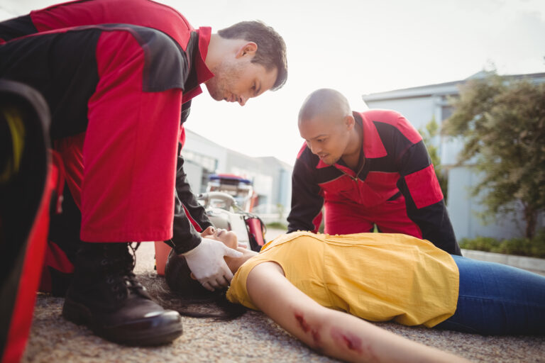 Paramedics examining injured woman on street