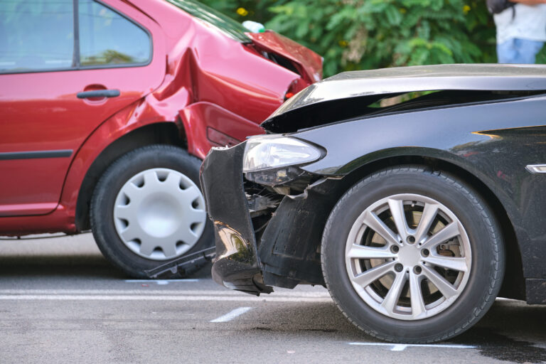 Damaged in heavy car accident vehicles after collision on city street crash site. Road safety and insurance concept.